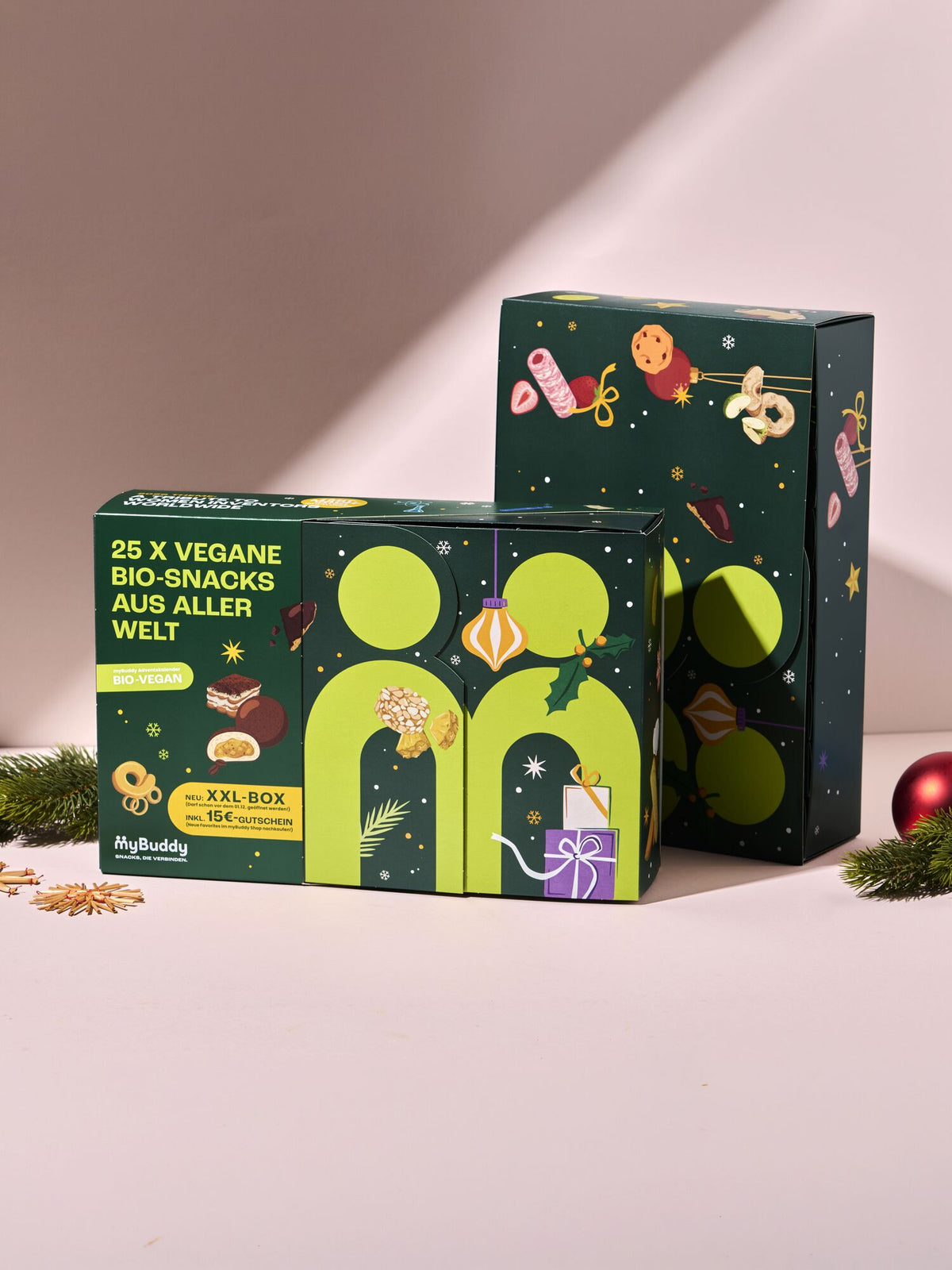 myBuddy Adventskalender 2026, BIO-VEGAN, zwei Verpackungen vor rosa Hintergrund