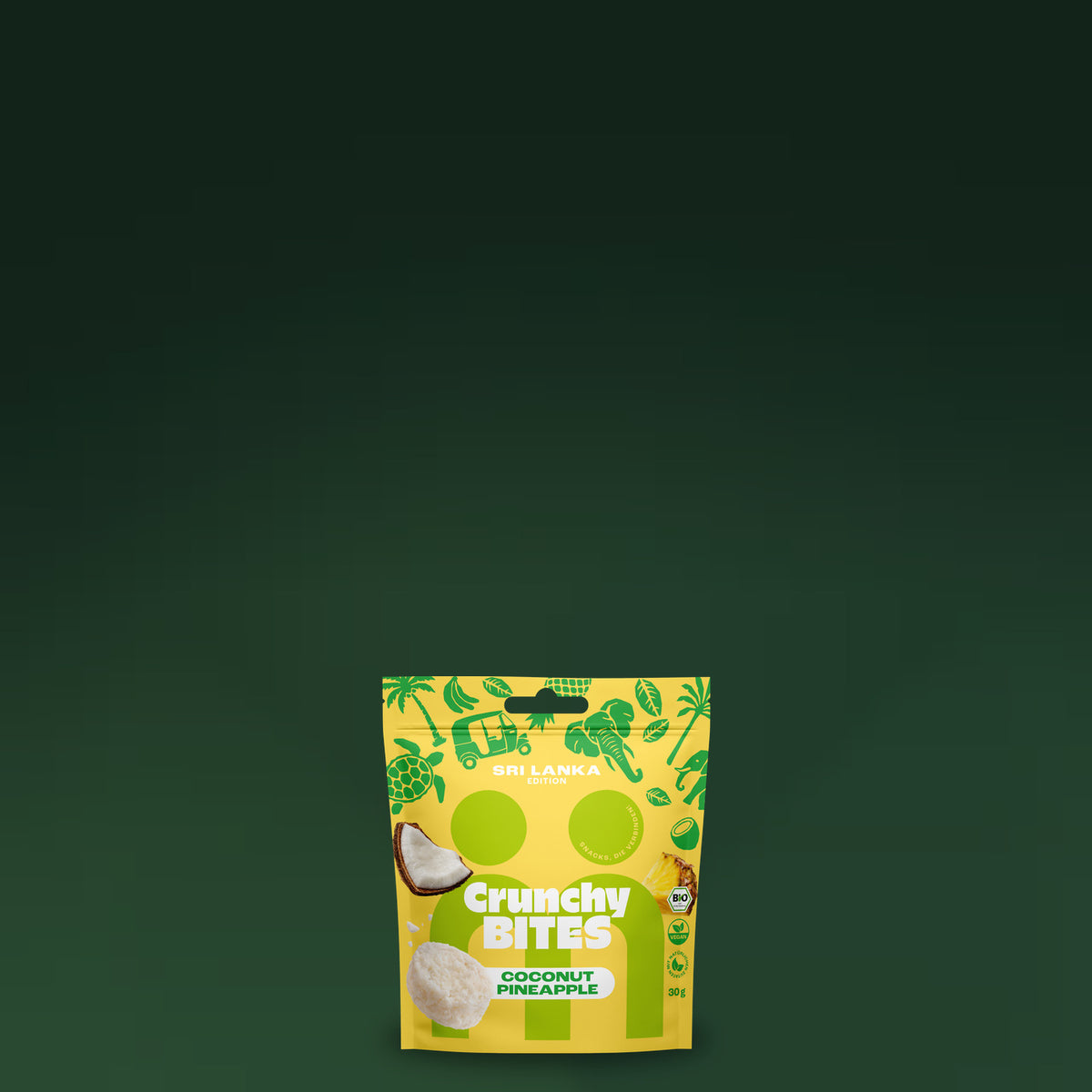 Crunchy Bites Coconut Pineapple Beutel vor dunkelgruenem Hintergrund