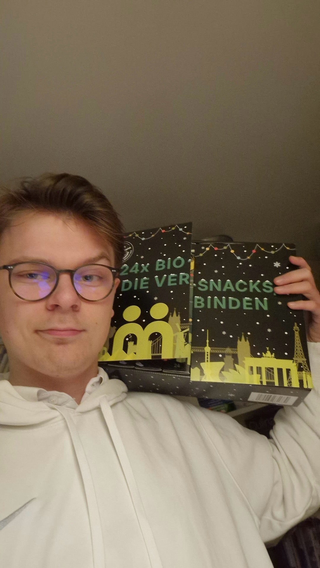 myBuddy Community-Foto: Junger Mann mit Brille im weißen Hoodie balanciert den aufgeklappten Kalender auf der Schulter