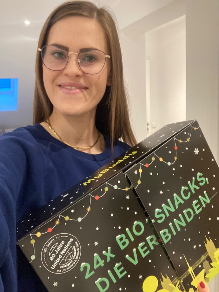 myBuddy Community-Foto: Frau mit Brille und Goldkette hält den Kalender schräg ins Selfie, helle Wohnung