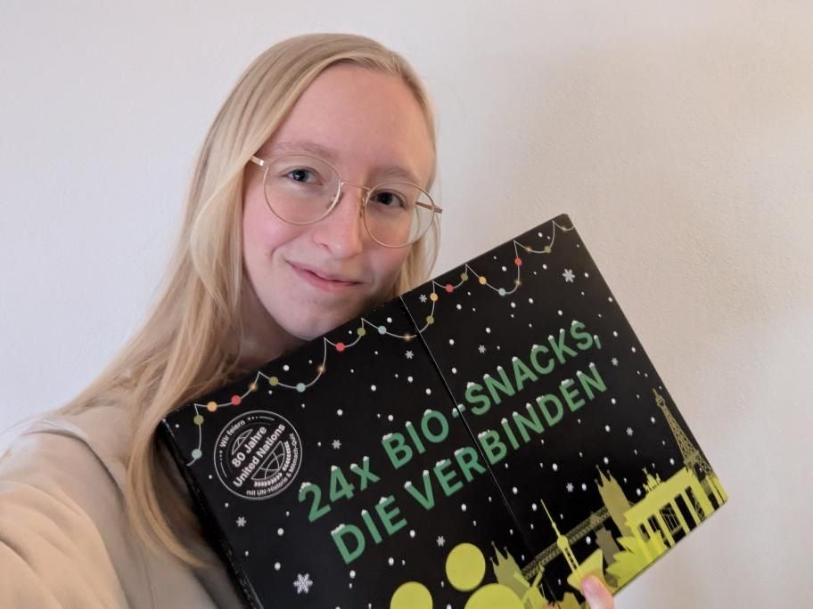 myBuddy Community-Foto: Blonde Frau mit Brille hält den Kalender vor weißer Wand ins Selfie
