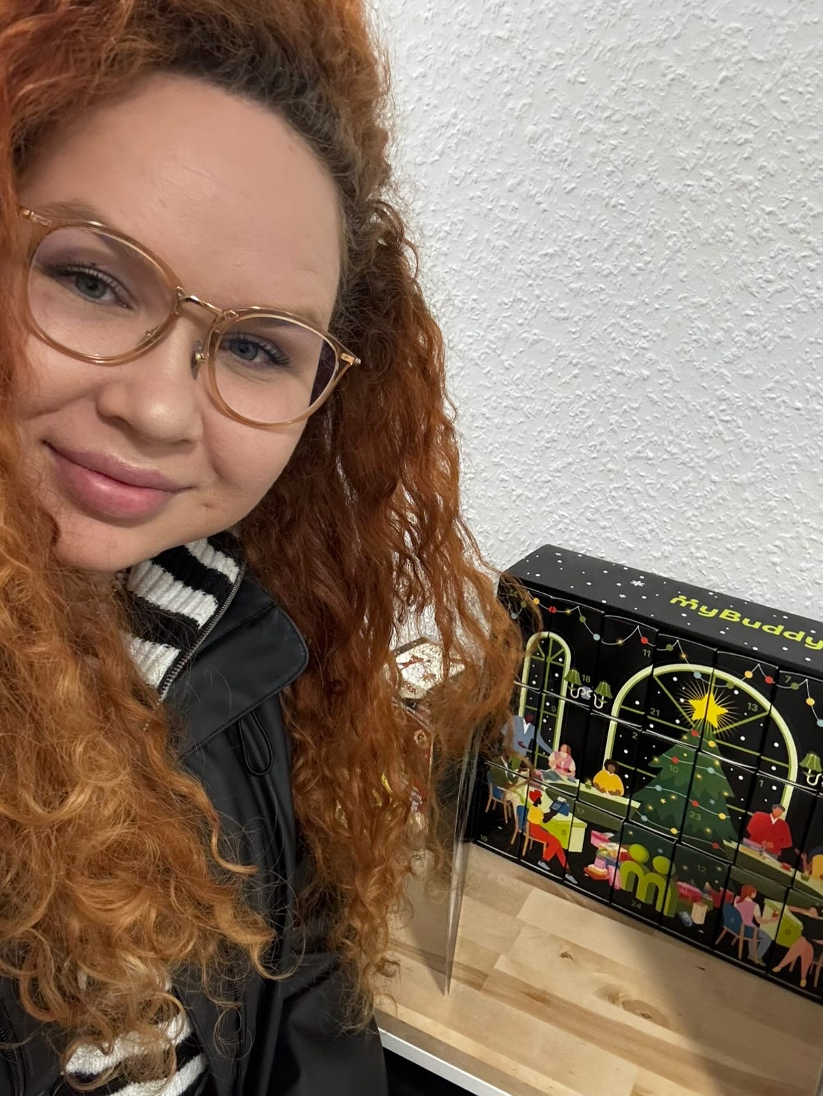 myBuddy Community-Foto: Rothaarige Frau mit Brille im Selfie, aufgeklappter Kalender auf dem Holztisch rechts